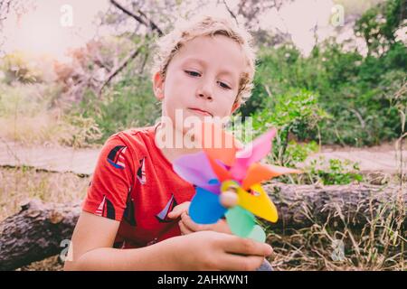 Enfant avec un regard d'émerveillement et d'étrangeté à la découverte d'un virevent. Banque D'Images