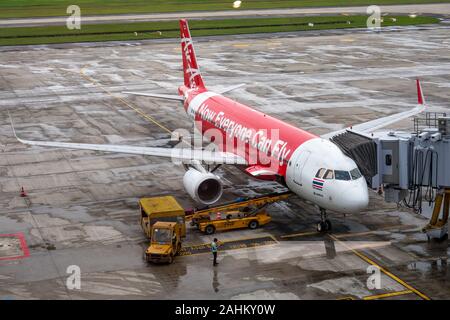 Un Airbus A320 de Thai AirAsia se trouve garé devant un portail et les personnels de charger les sacs sur un jour humide à Hanoi, l'Aéroport International de Noi Bai, Vietnam Banque D'Images