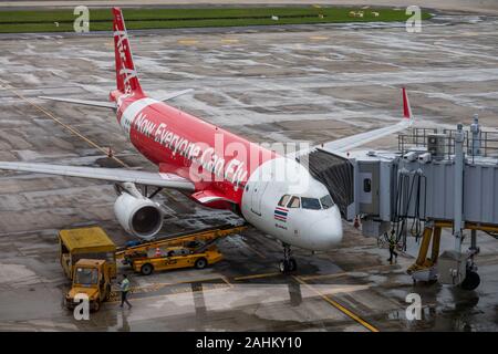 Un Airbus A320 de Thai AirAsia se trouve garé devant un portail et les personnels de charger les sacs sur un jour humide à Hanoi, l'Aéroport International de Noi Bai, Vietnam Banque D'Images