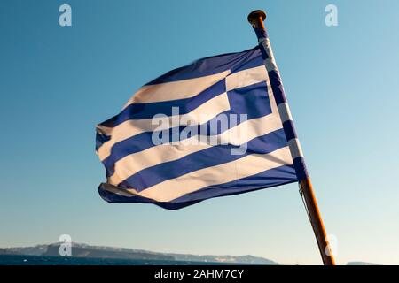 Le drapeau grec voltigeant dans le vent de l'arrière d'un voilier dans les îles grecques, près de l'île de Santorin en Grèce. Banque D'Images