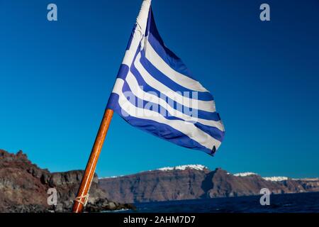 Le drapeau grec voltigeant dans le vent de l'arrière d'un voilier dans les îles grecques, près de l'île de Santorin en Grèce. Banque D'Images