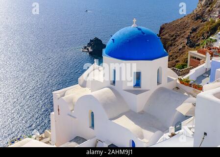 L'église au dôme bleu et blanc traditionnel face à la mer Egée maisons à Oia, Santorin, Grèce Banque D'Images