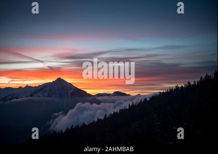 Coucher du soleil d'hiver coloré avec le Mont Niesen, les nuages et la forêt Banque D'Images