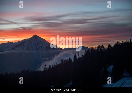 Coucher du soleil d'hiver coloré avec le Mont Niesen, les nuages et la forêt Banque D'Images