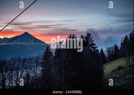 Coucher du soleil d'hiver coloré avec le Mont Niesen, les nuages et la forêt Banque D'Images