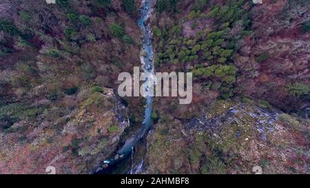 En vue de l'op d'un drone de la gorge de la rivière qui coule à travers un paysage alpin forêt brumeuse sur un hivers brumeux jour. Banque D'Images