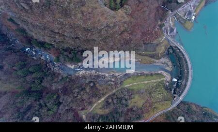 En vue de l'op d'un drone de la gorge de la rivière qui coule à travers un paysage alpin forêt brumeuse sur un hivers brumeux jour. Banque D'Images