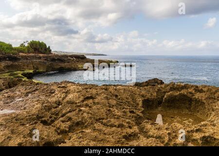 Rivage rocheux à Devil's larme sur île de Nusa Lembongan, à Bali, Indonésie. Côte Rocheuse avec cuvette en premier plan. L'océan, littoral, ciel & nuages Banque D'Images