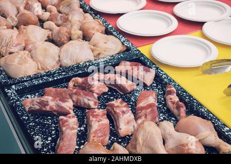 Morceaux de viande et les cuisses de poulet sur une plaque avant la cuisson Banque D'Images