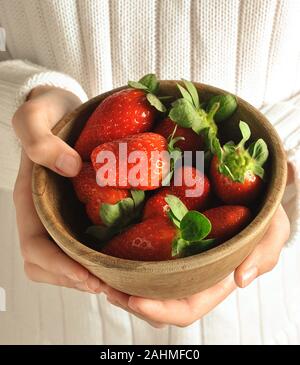 Fraises entre les mains des enfants. La fille tient des fraises entre les mains. Une alimentation saine Banque D'Images