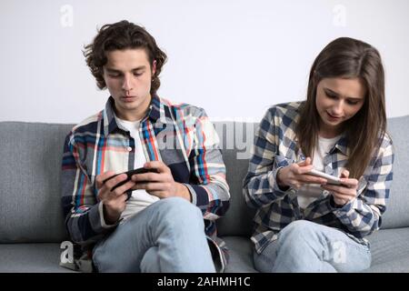 Concentré à l'aide de deux smartphones en salle de séjour. Banque D'Images