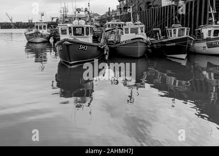 Le port de Scarborough. Les bateaux de pêche sont amarrés ensemble le long d'un quai. Leurs réflexions sont dans l'eau. Banque D'Images