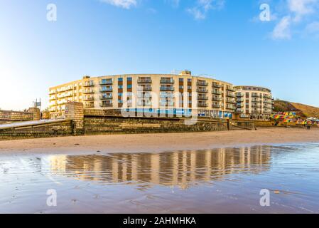 Plage du Nord, Scarborough. Un bâtiment s'élève au-dessus d'une plage et se reflète dans l'eau ci-dessous. Un ciel bleu est au-dessus. Banque D'Images