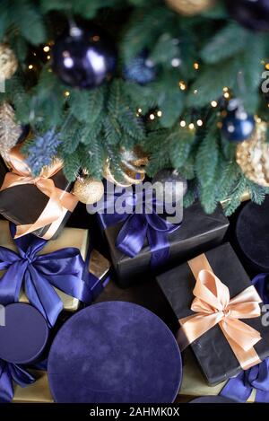 Une gamme de coffrets cadeaux près du pied de l'arbre de Noël. Boîtes en velours bleu Banque D'Images