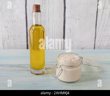 Homemade argan oil face cream, in a glass jar with a bottle of oil on the side, on a light wooden background Banque D'Images
