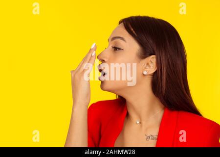 Woman sa respiration, l'odeur de la gomme avec sa main. Modèle de race mixte isolé sur fond jaune avec copie espace. Image horizontale. Naturelle, makeu Banque D'Images