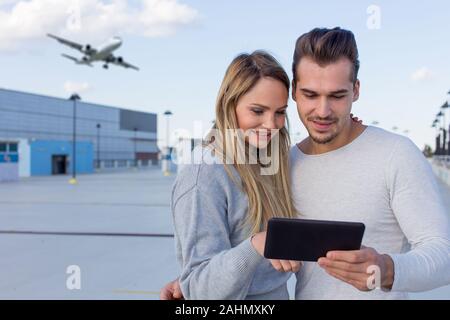 Young caucasian couple commander ticket de l'air par l'app on digital tablet outdoors Banque D'Images