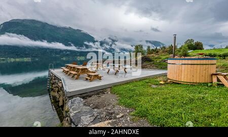 Jacuzzi et une zone de baignade dans la frontière de Lustrafjorden, Hoyheimsvik, la Norvège. Modèle de brouillard et les montagnes sont reflétant dans l'eau miroir du Fjord Banque D'Images