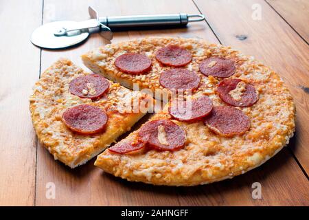 Pepperoni et fromage pizza sur une planche de bois avec une pizza cutter Banque D'Images