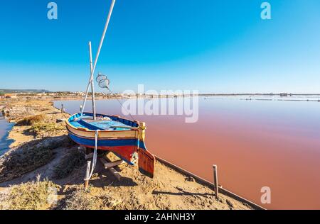 L'île saline de Saint Martin de Gruissans, le vieux bateau en bois à gauche et la saturation de couleur rougeâtre à l'eau salée dans la droite. Occitanie, France Banque D'Images