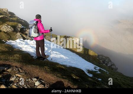 Coniston, Lake District, Cumbria UK. Le 31 décembre 2019. Météo britannique. Un phénomène spectaculaire walker jouit de la d'un spectre du Brocken le dernier jour de 2019. Ces arcs-en-ciel comme halo sont également appelées une gloire par les météorologues. Ils contiennent l'ombre d'une personne et sont causées par le soleil casting l'ombre de l'observateur sur la brume ou les nuages au-dessous d'eux, tandis que le halo est causée par la diffraction. Crédit : David Forster/Alamy Live News Banque D'Images