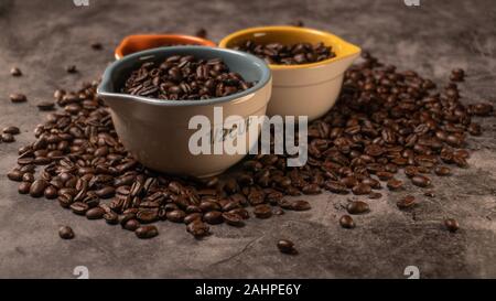 Les grains de café organiques Matières premières fraîches dans un grand nombre de tasses colorées avec des tailles variées Banque D'Images