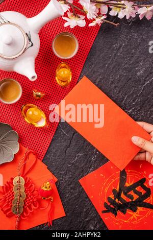 Concept de design janvier Nouvel An lunaire chinois - Woman holding, donner des enveloppes rouges (ang pow, hong bao) pour la chance de l'argent, top vue, télévision lay, overhe Banque D'Images