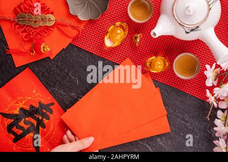 Concept de design janvier Nouvel An lunaire chinois - Woman holding, donner des enveloppes rouges (ang pow, hong bao) pour la chance de l'argent, top vue, télévision lay, overhe Banque D'Images