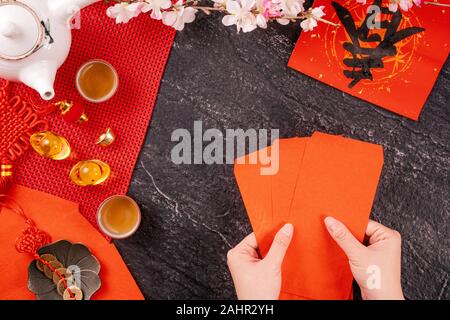 Concept de design janvier Nouvel An lunaire chinois - Woman holding, donner des enveloppes rouges (ang pow, hong bao) pour la chance de l'argent, top vue, télévision lay, overhe Banque D'Images