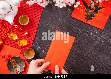 Concept de design janvier Nouvel An lunaire chinois - Woman holding, donner des enveloppes rouges (ang pow, hong bao) pour la chance de l'argent, top vue, télévision lay, overhe Banque D'Images