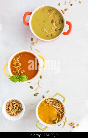 Une vue du haut vers le bas de trois bols de soupe saupoudrée de nouilles croquantes et graines de citrouille pour garnir. Banque D'Images