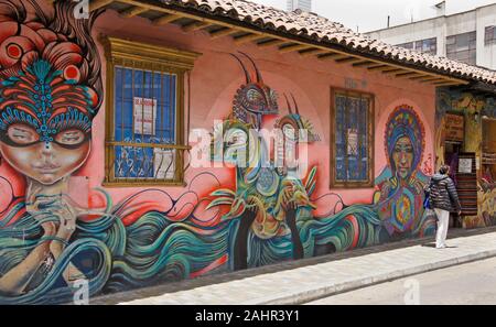 Femme marche passé par l'artiste urbain Rodez et graffiti peint sur l'extérieur du bâtiment dans le quartier de La Candelaria de Bogota, Colombie Banque D'Images