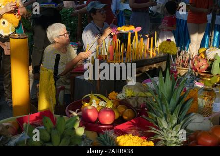 Fidèles à un culte à l'extérieur de la ville Pilier de culte bâtiment (Lak Muang, Lak Mueang), à Bangkok, Thaïlande, entouré par des offrandes sacrificielles Banque D'Images