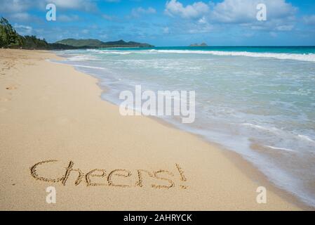 Cheers écrit dans le sable sur Waimanalo Beach à Hawaii avec l'océan en arrière-plan Banque D'Images