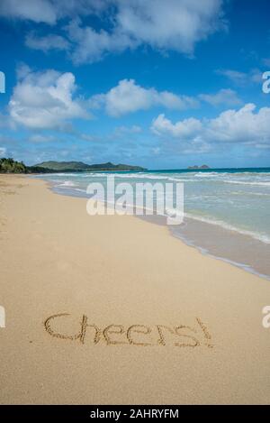 Cheers écrit dans le sable sur Waimanalo Beach à Hawaii avec l'océan en arrière-plan Banque D'Images
