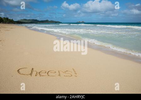 Cheers écrit dans le sable sur Waimanalo Beach à Hawaii avec l'océan en arrière-plan Banque D'Images