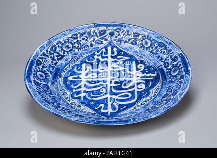 Islamique. Le plat. 1822-1823. L'Iran. Fritware, peint en bleu sous une glaçure transparente la palette de couleurs et dessins naturalistes de ce plat sont un témoignage de l'influence durable de la porcelaine chinoise sur la céramique du monde islamique. Ce plat dispose de décorations florales dans un style naturaliste et le chinois traditionnel dans des tons bleus et blancs. Le motif central du plat calligraphiques, offrant des paroles pieuses, est écrit en caractères arabes, mais sa forme rappelle les caractères chinois. L'influence chinoise sur la céramique islamique peut être vu dès le 9e siècle, et c'est poursuivie jusqu' Banque D'Images