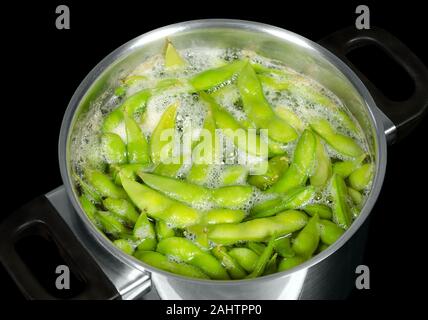 Le soja vert, edamame, maodou, ébullition dans l'eau salée dans un chaudron. Le soja, Glycine max, une légumineuse riche en protéines que le bis. Banque D'Images