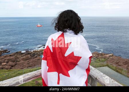 En tourisme d'un drapeau canadien à Cape Spear, à Terre-Neuve et Labrador, Canada. L'emplacement est le point le plus à l'est en Amérique du Nord. Banque D'Images
