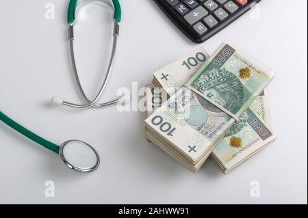 Pile de billets d'origine polonaise, stéthoscope et calculateur sur le tableau blanc. Services médicaux concept financier Banque D'Images