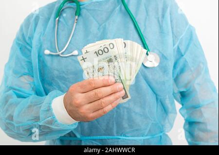 Médecin part holding pile of Polish zloty billets. Services médicaux concept financier Banque D'Images