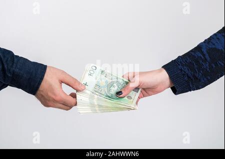Close up of woman part donner des tas d'origine polonaise à l'homme de main. Arrière-plan blanc. Billets d'origine polonaise. Zloty polonais PLN 100 Banque D'Images