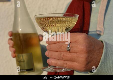 Femme tenant un verre de cristal et une bouteille de Cava Freixenet lors d'une fête Banque D'Images