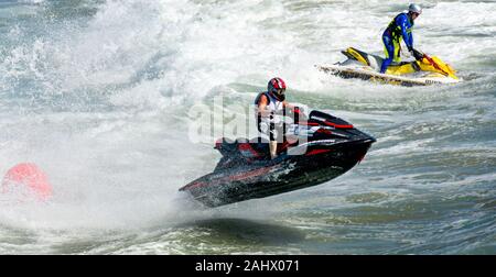 Deux skieurs jet racing à pleine vitesse dans l'océan. Le jet skieur dans l'avant-plan est l'air. Les deux hommes sont debout dans leur jet ski. Banque D'Images