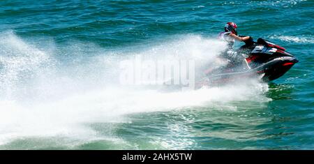 Un homme est un jet ski de course à pleine vitesse dans l'océan et de la création d'un grand service derrière lui. Banque D'Images