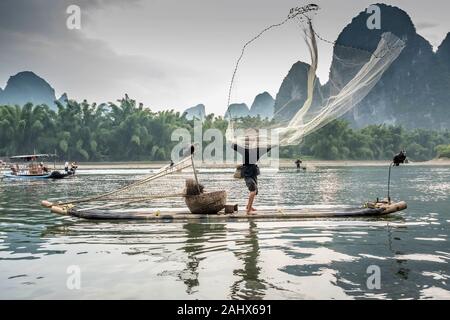 Pêcheur jetant un filet de fonte élevé dans l'air, Li River près de Xingping, province de Guangxi, Chine Banque D'Images