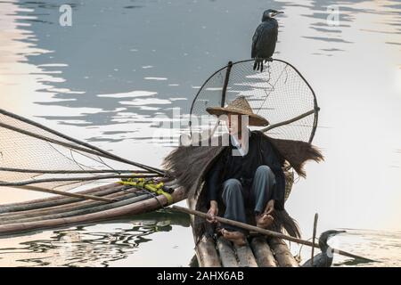 Portrait d'un pêcheur cormorant assis sur un radeau de bambou, rivière Li, Xingping, province de Guangxi, Chine Banque D'Images
