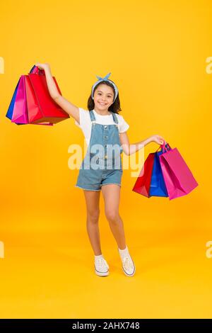 Traiter avec succès. Hurry up. Acheter plus rapidement. Happy girl with shopping bags. Petit enfant sourire avec des sacs en papier. Préparation et célébration des fêtes. Shopping sur le black friday. Shopping d'inspiration. Banque D'Images