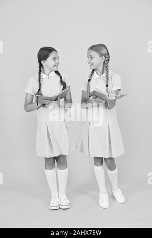 Intérêt sincère. Bibliothèque de l'école. Des livres éducatifs pour l'école. La lecture de livres. La lecture et l'interprétation. Les petits enfants holding books fond jaune. Peu de filles avec des livres pour enfants ou de l'encyclopédie. Banque D'Images