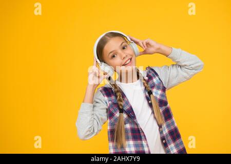 Happy little girl wearing headphones moderne. Cute kid bénéficiant d'un son stéréo. C'est la liberté sans fil. Avec la technologie sans fil. Petit enfant à écouter de la musique sans fil moderne d'écouteurs. Banque D'Images